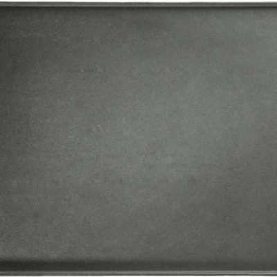 Plaque de cuisson réversible en fonte émaillée Napoléon posée sur barbecue, avec surface nervurée et trous de drainage visibles